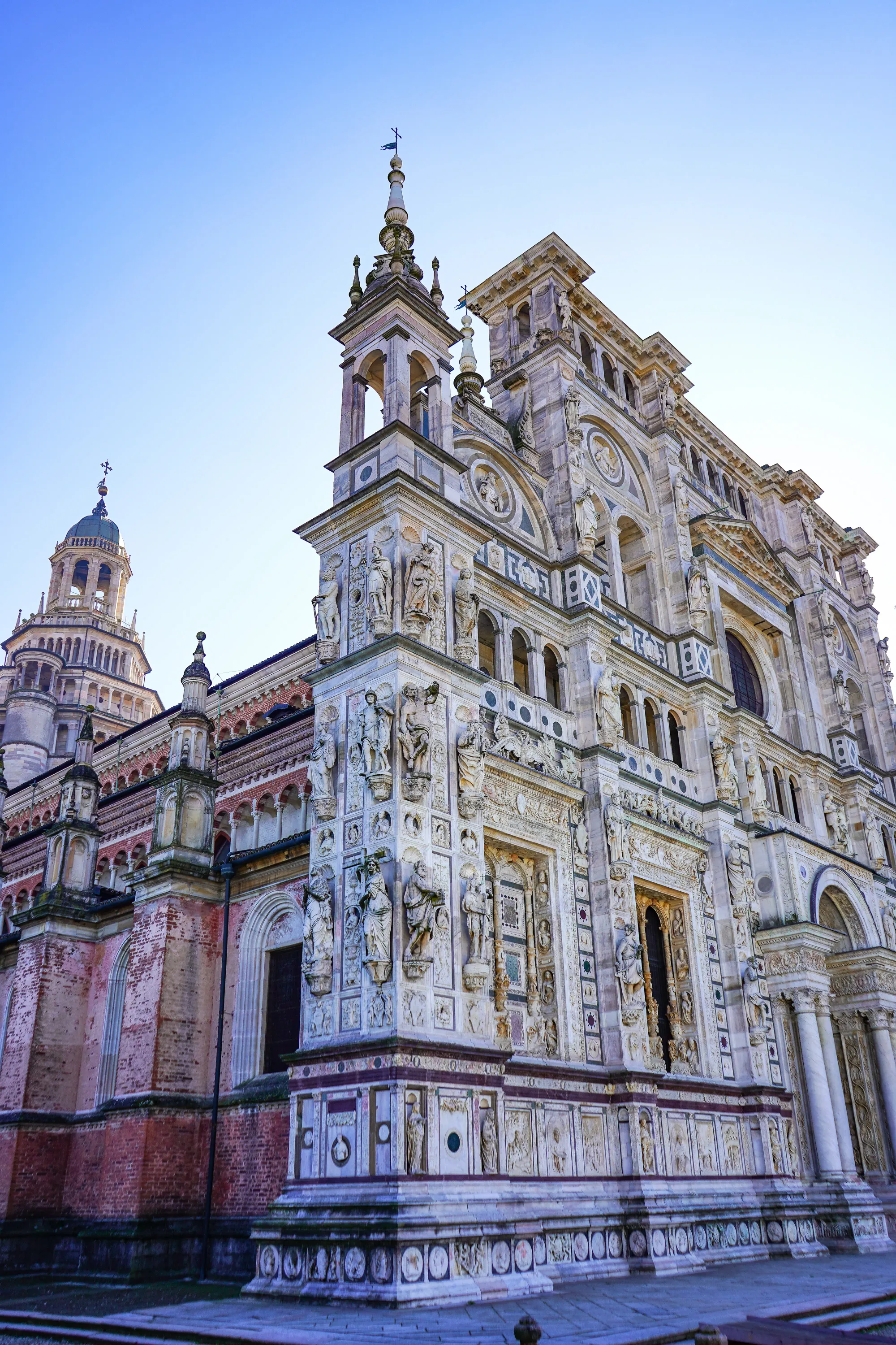 The intricately carved white marble facade of the Certosa di Pavia church, covered in saints and bas-reliefs