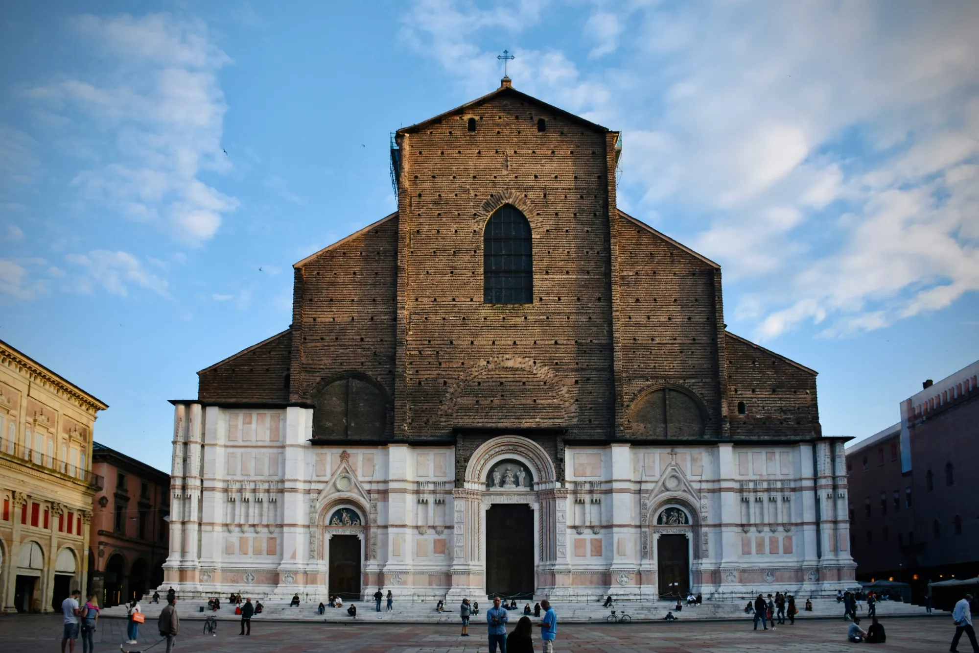 Basilica di San Petronio, with half the facade in red and white marble panel and the upper half in bare brick.