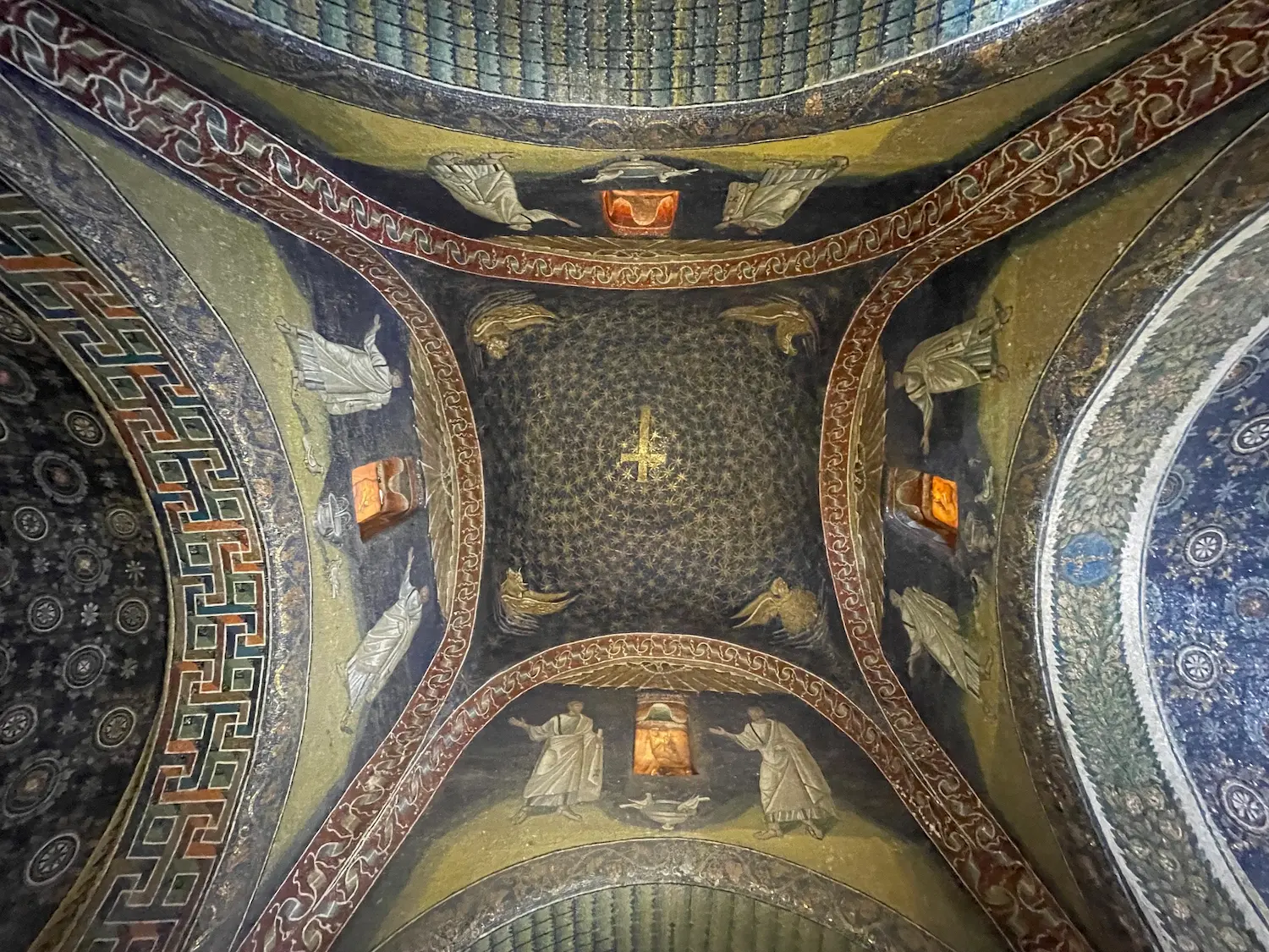 The star-scattered dome of the Mausoleum of Galla Placidia, Ravenna - a golden cross set against deep blue mosaic, with the four evangelist symbols in the corners