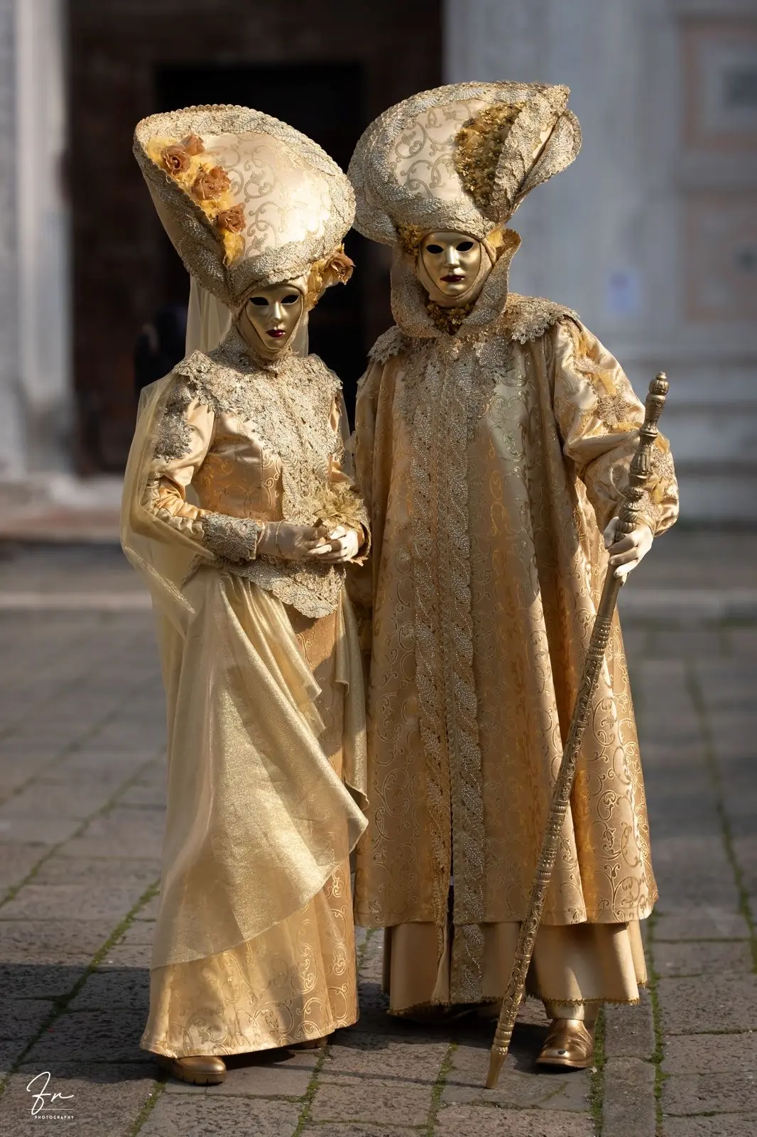 Couple in matching gold and cream Carnival costumes with fan-shaped headdresses, Venice