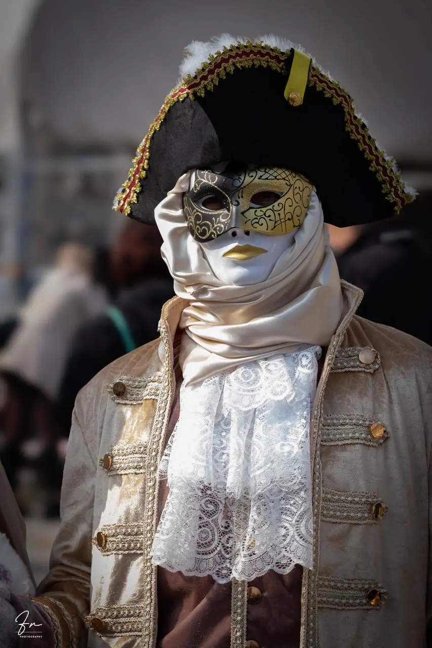 Carnival reveller in gold filigree mask, tricorn hat and white lace scarf, Venice